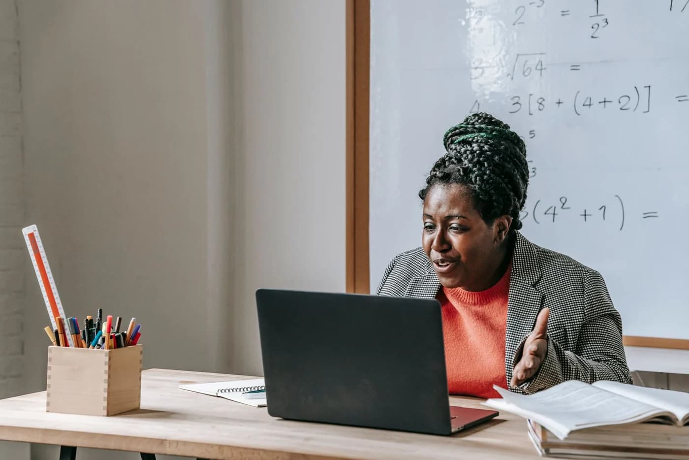 A teacher explaining a maths lesson over her laptop
